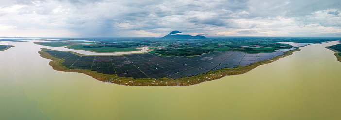 Aerial view of large sustainable electrical power plant with many rows of solar photovoltaic panels for producing clean ecological electric energy in countryside with cloudy sky in Tay Ninh, Vietnam