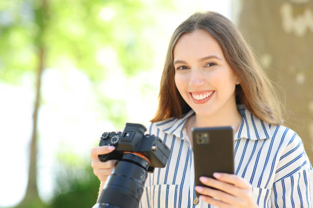 istock Happy photographer holds camera and phone posing 1593746125
