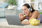 Funny woman eating chips watching online videos