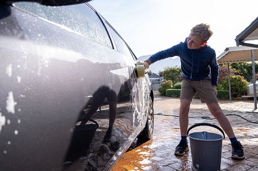 Young boy washing his Dad's car for pocket money.