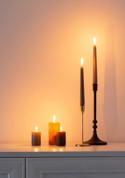 istock burning candles on white wooden shelf in white interior 1593758962