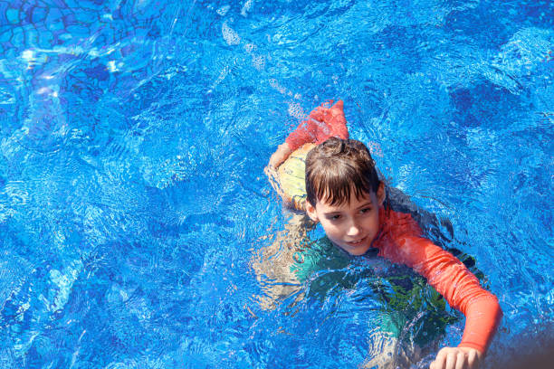 istock a school-age boy playing ball in a swimming pool 1593772814