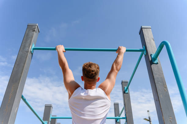 istock A young man pulls himself up on a horizontal bar on a street sports ground. 1593816533