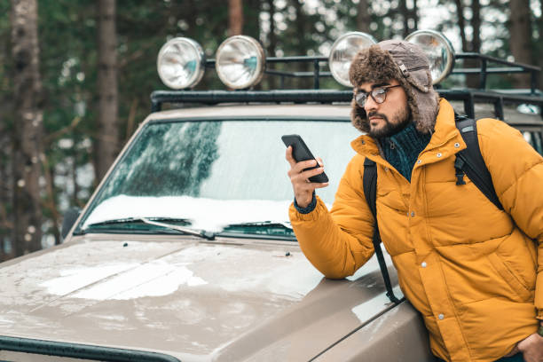 istock Young handsome male using mobile phone next to a jeep in the forest 1593820377
