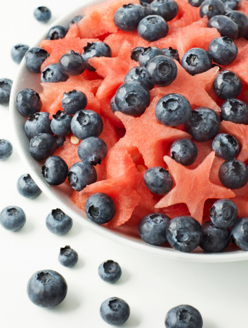 Watermelon and blueberry salad in a white bowl on a white background.