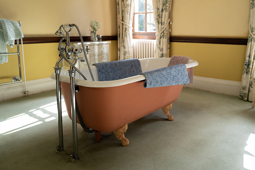 Stylish old-fashioned bathtub and chrome taps seen in an old English mansion house.