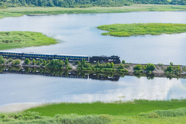 istock Retro steam train moves along the lake. 1593860358