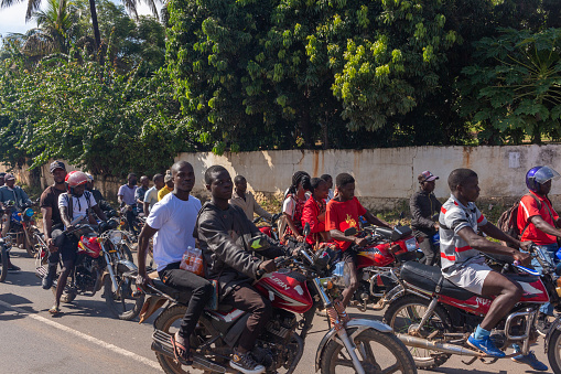 Manica, Mozambique - April 7, 2022: Motorbike taxi drivers transporting people on a street with a lot of traffic