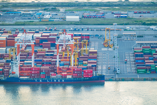 aerial top down view of a container ship in terminal at the port, where massive containers await their journey
