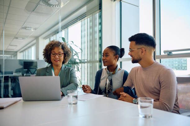 istock Happy insurance agent using laptop while having a meeting with young couple in the office. 1593908025