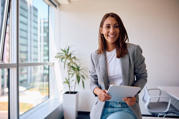 istock Young happy businesswoman using touchpad while working in the office and looking at camera. 1593915123
