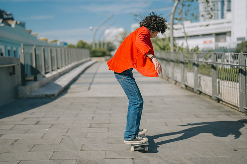 Asian Malay young man practicing skateboarding at pedestrian walkway during weekend morning