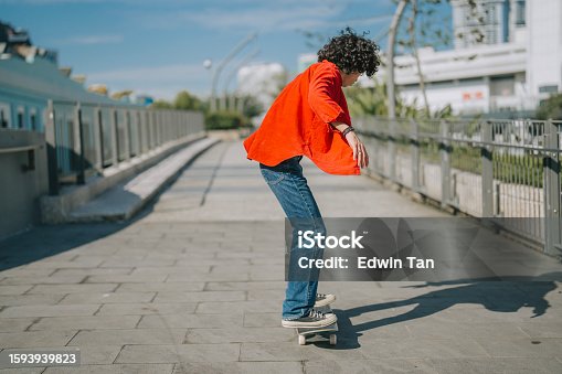 istock Asian Malay young man practicing skateboarding at pedestrian walkway during weekend morning 1593939823