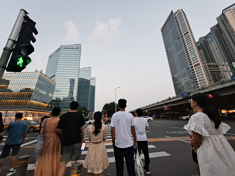 Beijing, China – August 5, 2023: Pedestrians waiting to cross road among commercial buildings in Central Business District.