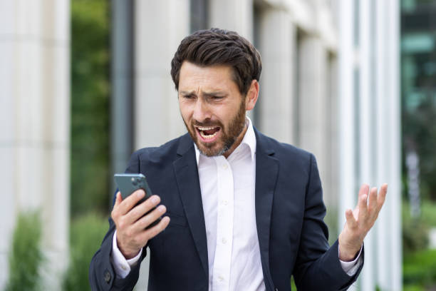 verärgerter trauriger geschäftsmann, der schlechte nachrichten online mit app auf dem telefon liest, denkender mann außerhalb des bürogebäudes enttäuscht von den leistungsergebnissen am arbeitsplatz, chef deprimiert - quit scene stock-fotos und bilder