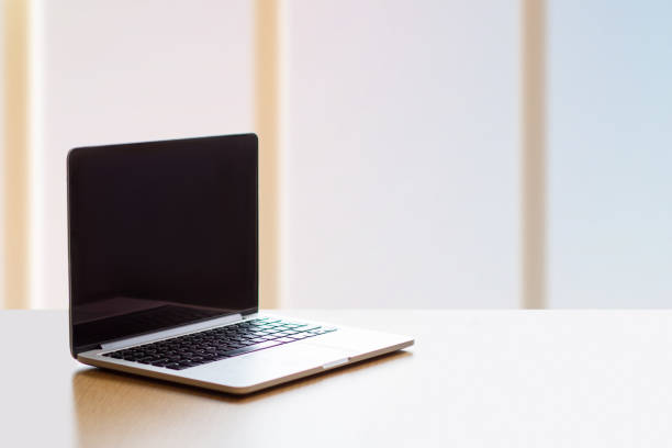 istock Laptop with black screen on an empty long table by the window 1594010606