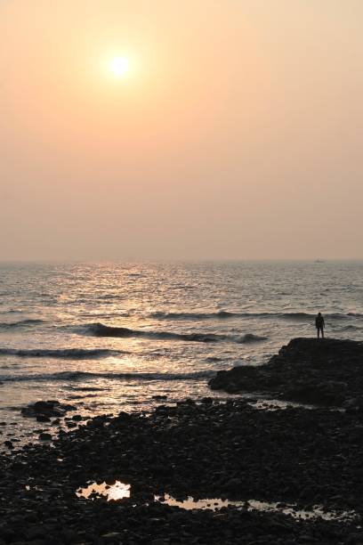 A person observing the sunset by the Arabian Sea in Mumbai, India.