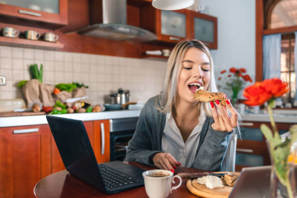 istock Happy woman eating while working at home office 1594035062