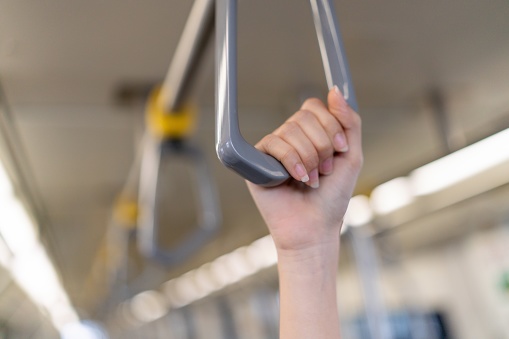 In the urban journey, a woman’s hand securely grips the handrail, embodying the essence of the daily commute