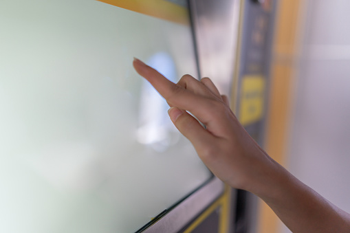 Close up photo view of a hand selecting on the ticketing machine of the monorail train station
