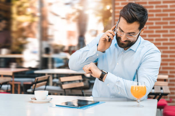 Businessman using phone and looking at wrist watch