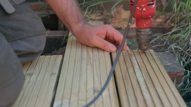 Male builder using drill to screw the screws off the timber