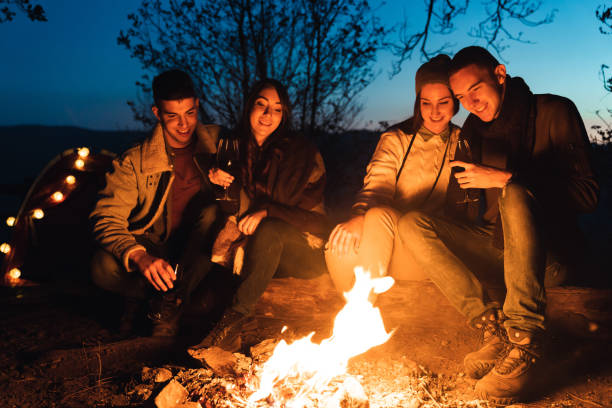 istock Happy couples camping and relaxing around a bonfire 1594049962