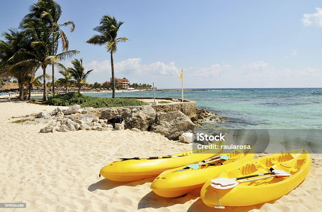 Kayaks by the beach Three yellow kayaks and paddles sit on the tropical white sandy beach town of Riviera Maya, Mexico Beach Stock Photo