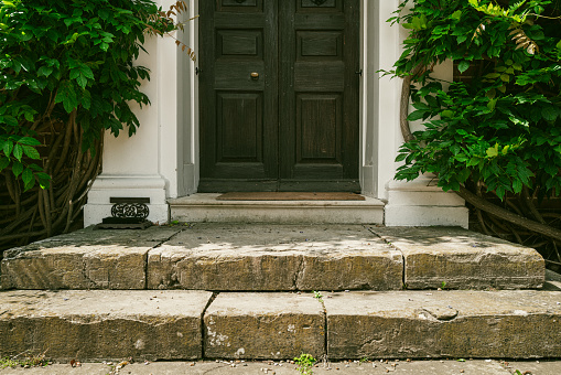Shallow focus of stone steps leading to the front wooden door of an old English Manor House.