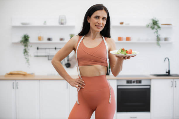 istock Fit lady posing on camera with fresh salad and smiling 1594114128