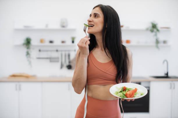 istock Brunette trying salad from fresh vegetables and greens 1594114311