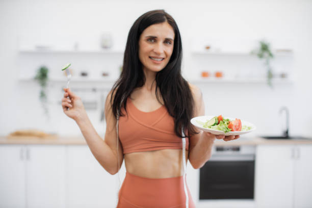 istock Active woman smelling fresh vegetables after workout at home 1594114645