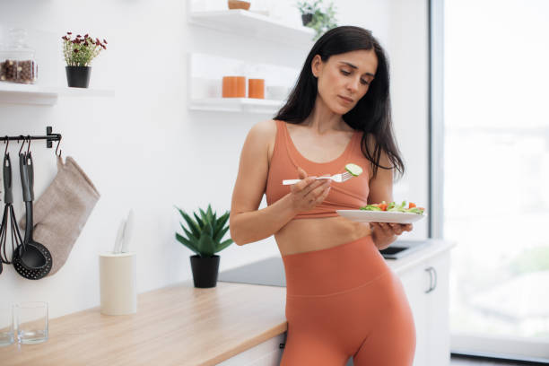 istock Fitness lady looking at plate with greens in modern kitchen 1594114672