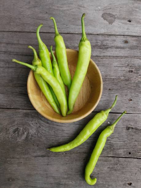 istock Green chilli plant on wood background 1594118019