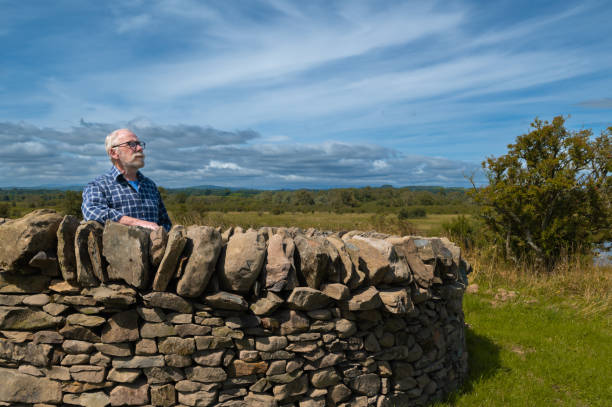 istock Senior man standing behind a stone wall 1594118342