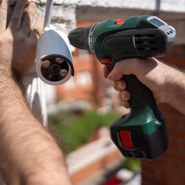 mann mit einem bohrer, der überwachungskameras zur überwachung in einem haus installiert. - vertical security camera security system security stock-fotos und bilder