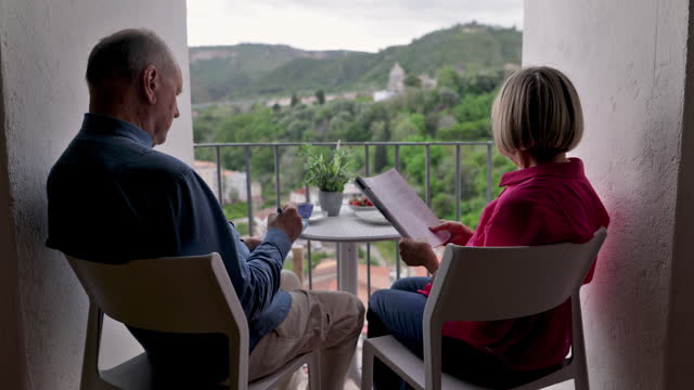 Senior couple relaxing on balcony and sipping coffee