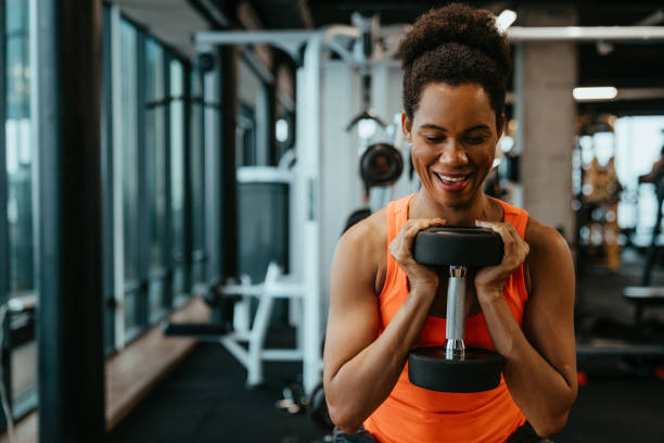 istock Young motivated sportswoman with sweat doing exercises, lifting weights, working out with dumbbell 1594151659