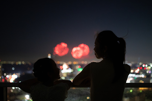 Mother and daughter watching fireworks from balcony