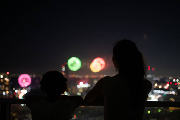 Mother and daughter watching fireworks from balcony