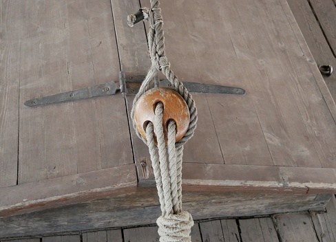 Rigging on a ship made according to ancient technologies. Rope made of natural materials on a wooden block on the deck of an ancient ship.