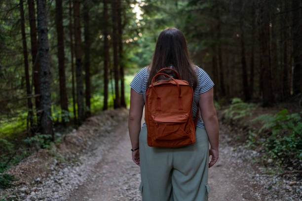 istock Rear view of young casually clothed woman with backpack exploring forest alone 1594170413