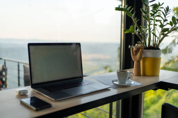 istock Laptop, mobile phone and coffee cup on a table with a view 1594171533