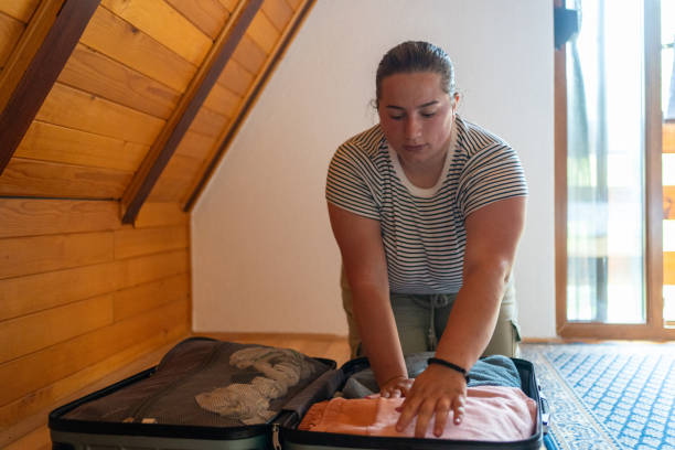 istock Young casually clothed woman packing suitcase at log cabin 1594178528