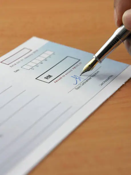 Closeup of a pen on a cheque book on white background