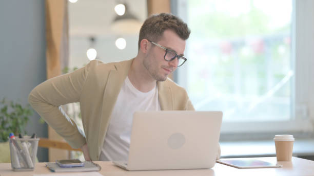 istock Young Businessman with Back Pain Working on Laptop 1594188610