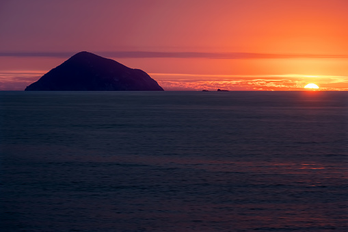 The sun setting over the horizon at sea.