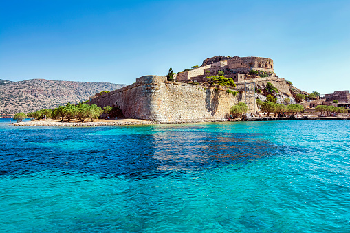 Panoramic view of the island of Spinalonga with calm sea. Here were isolated lepers, humans with Hansen's disease, gulf of Elounda, Crete, Greece.