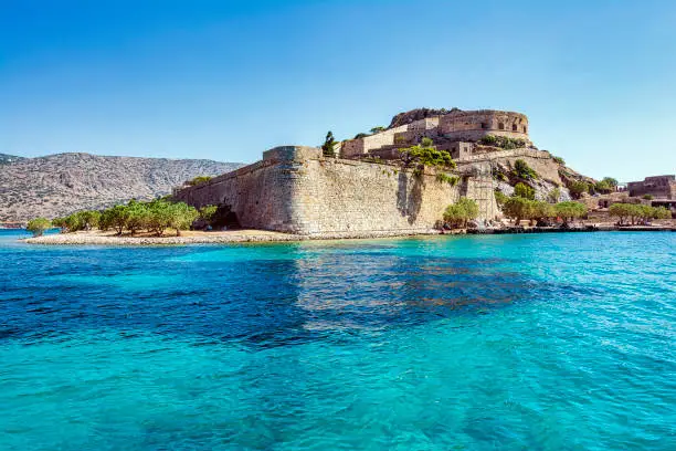 Panoramic view of the island of Spinalonga with calm sea. Here were isolated lepers, humans with Hansen's disease, gulf of Elounda, Crete, Greece.