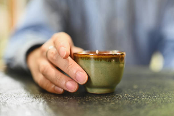 istock Close up and cropped image of man's hands holding a small traditional ceramic tea cup. 1594230252